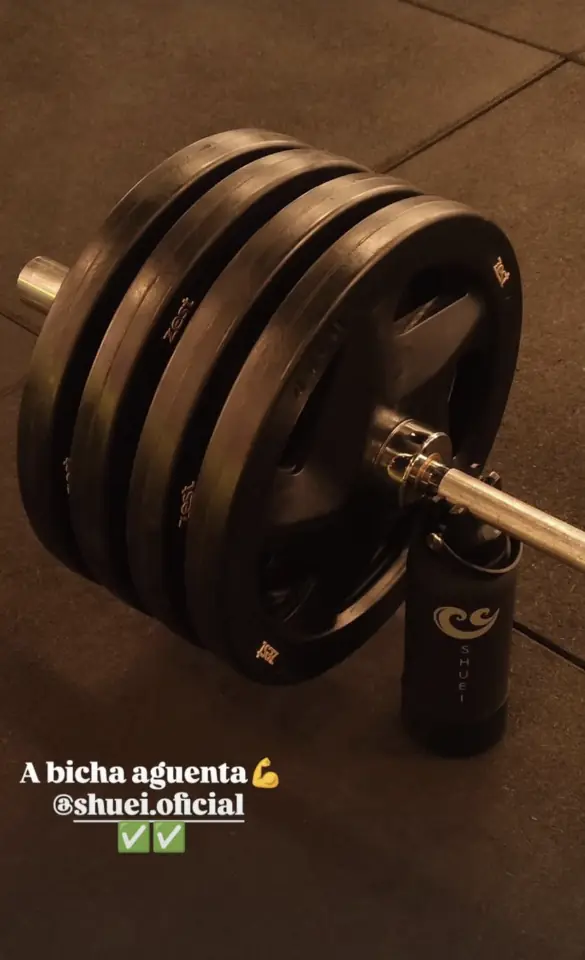 Garrafa SHUEI apoiando a barra carregada para a troca de anilhas: “A bicha aguenta”